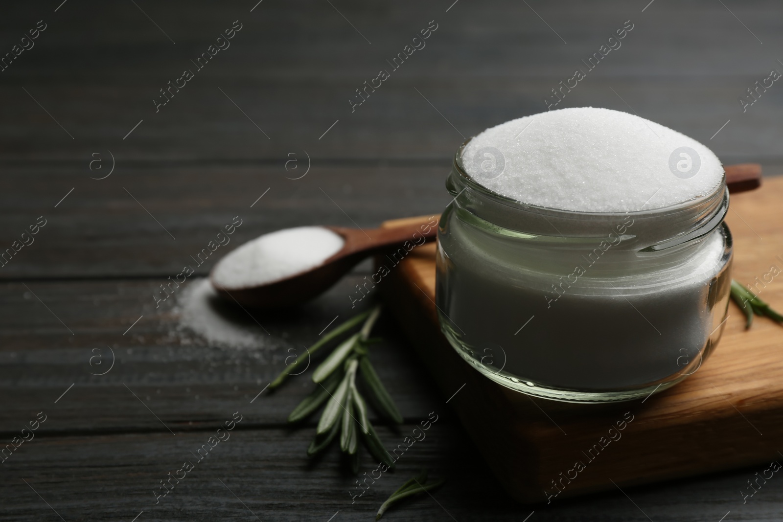 Photo of Glass jar with salt on black wooden table, closeup