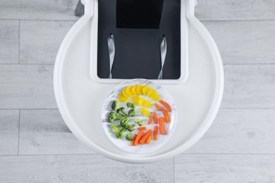 Photo of High chair with healthy baby food served on white tray indoors, top view