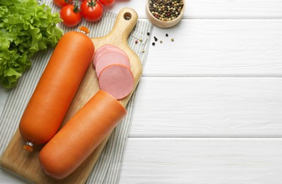 Photo of Board with tasty boiled sausages and products on white wooden table, flat lay. Space for text