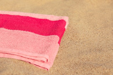 Photo of Soft pink beach towel on sand, space for text
