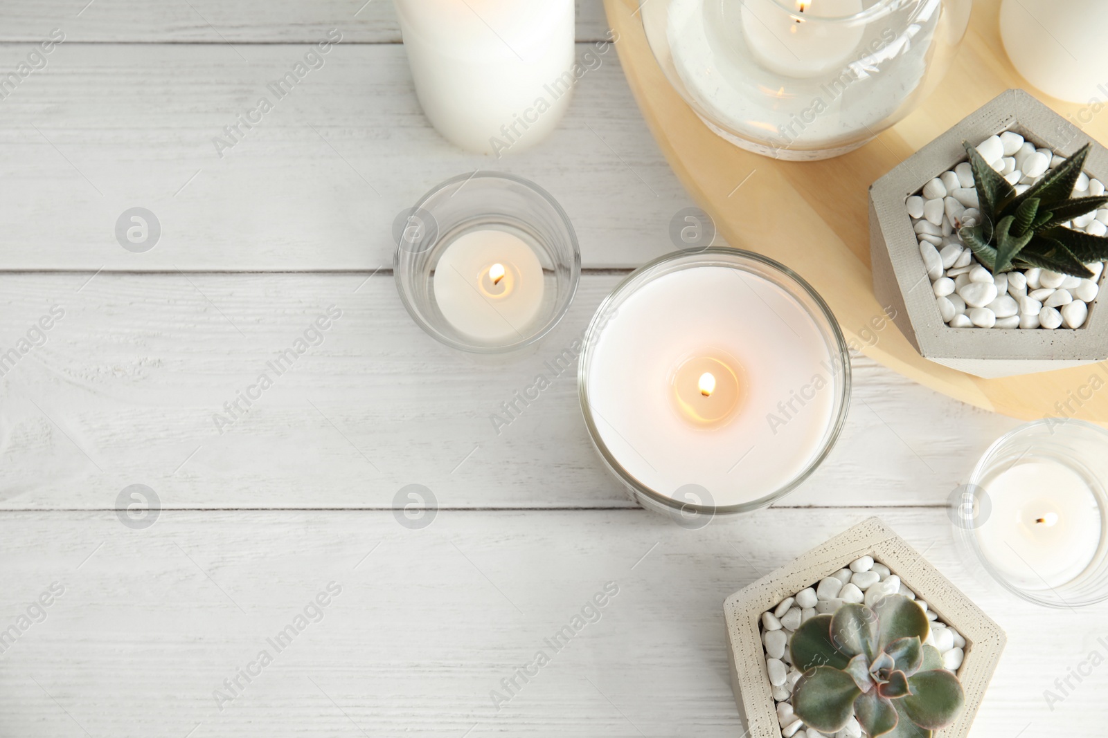 Photo of Flat lay composition with burning aromatic candles and plants on wooden table. Space for text