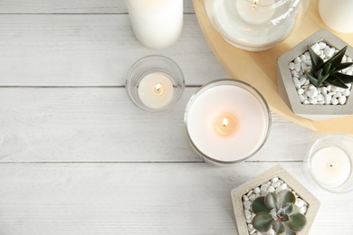 Flat lay composition with burning aromatic candles and plants on wooden table. Space for text