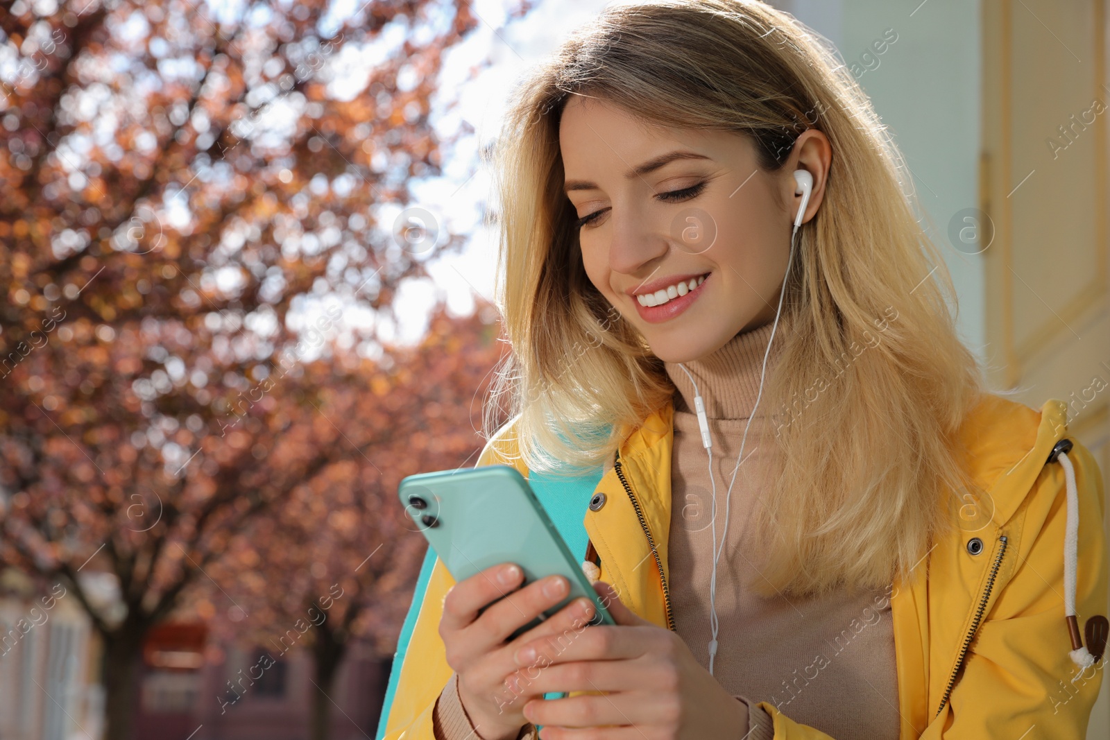 Photo of Young woman listening to audiobook on city street
