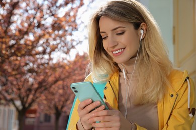 Young woman listening to audiobook on city street