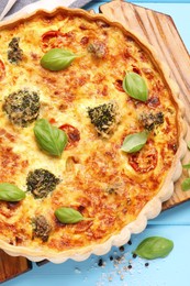 Delicious homemade vegetable quiche on light blue table, top view