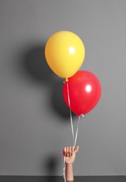 Photo of Wooden hand holding colorful balloons on gray background