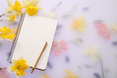 Photo of Guest list. Notebook, pen and daffodils on spring floral background, flat lay. Space for text