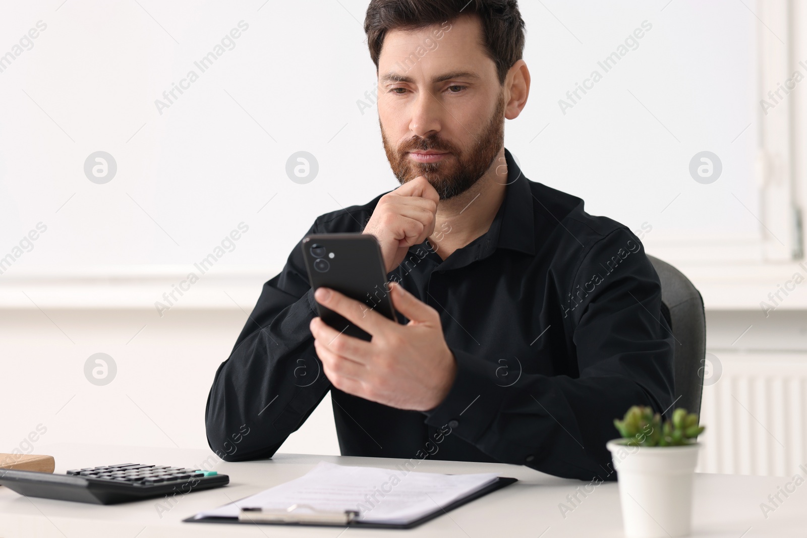 Photo of Handsome man using smartphone at table in office