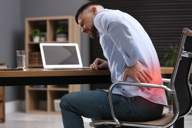 Image of Man suffering from back pain while working with laptop in office. Symptom of poor posture
