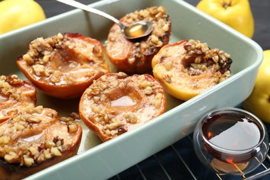Photo of Tasty baked quinces with nuts and honey in dish on grid, closeup