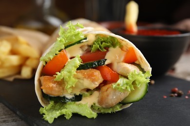 Delicious shawarma with chicken and fresh vegetables   on slate plate, closeup