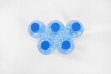 Plastic bottles with pure water on white background, top view