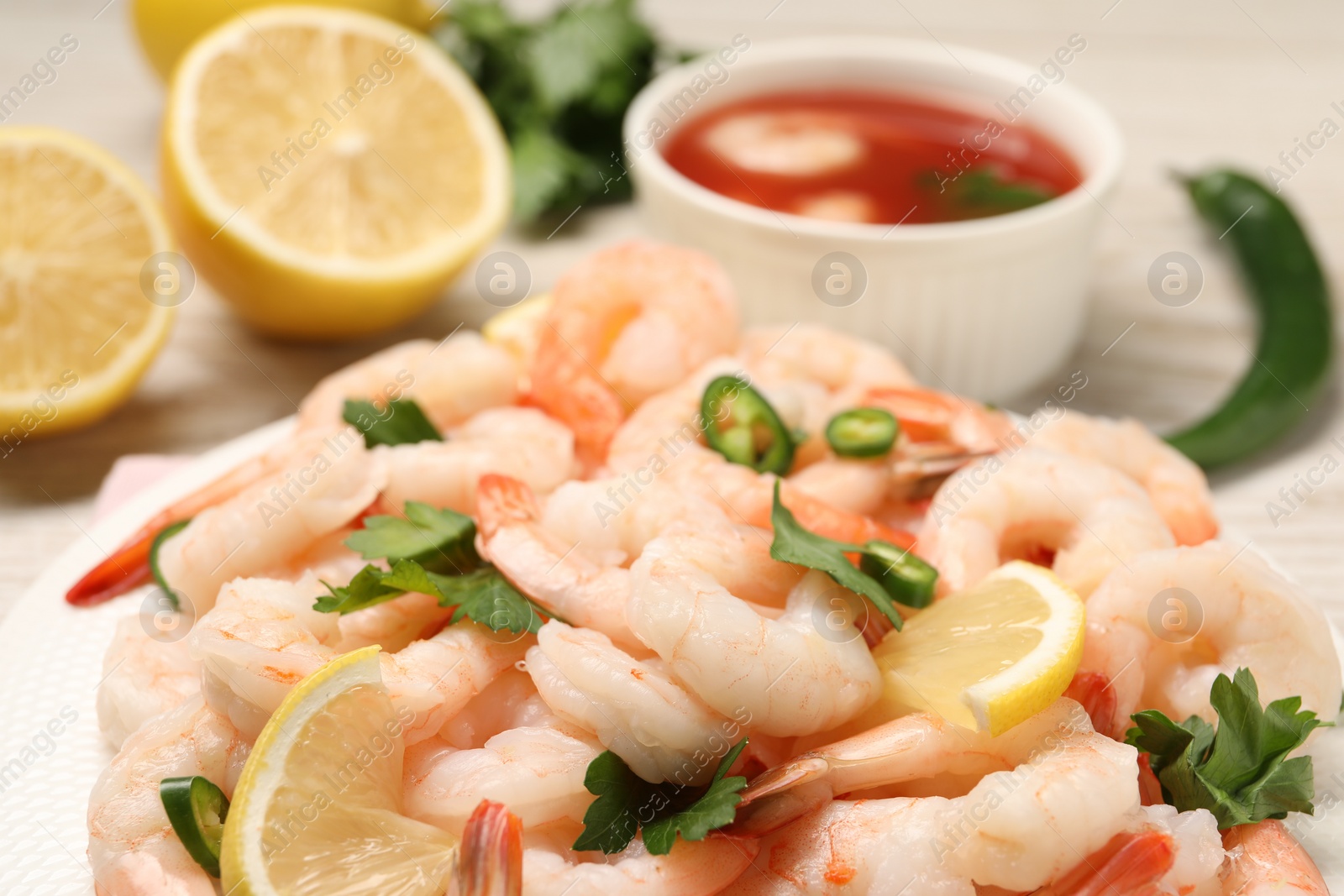 Photo of Tasty boiled shrimps with cocktail sauce, chili and parsley on table, closeup