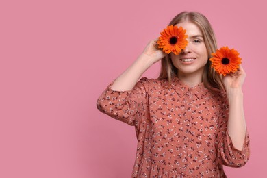 Beautiful woman with spring flowers in hands on pink background, space for text