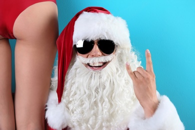 Photo of Young Santa Claus with sexy naked woman on color background