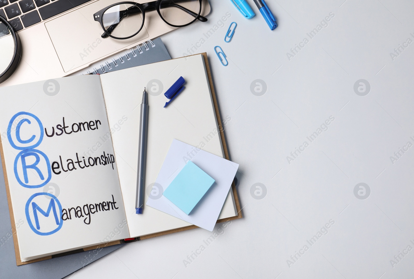 Photo of Notebook with CRM abbreviation and space for text on white office table, flat lay. Customer Relationship Management