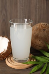 Glass of coconut water, leaf and nuts on wooden table