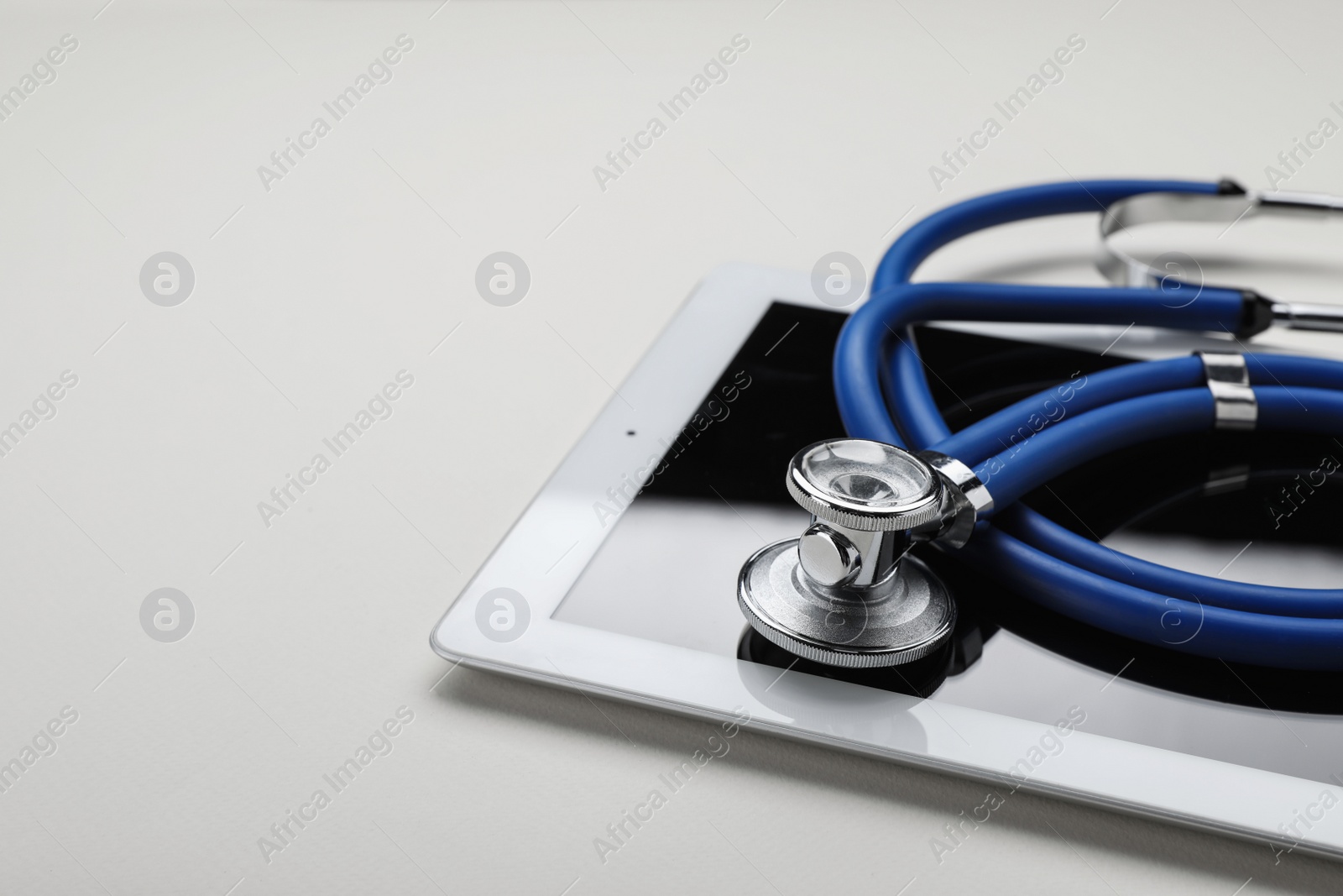 Photo of Medical stethoscope and tablet on beige background, closeup. Space for text
