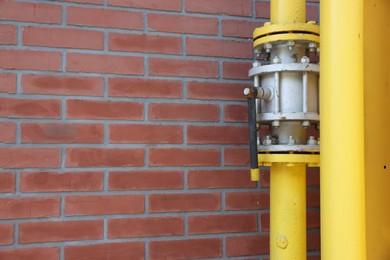 Photo of Yellow gas pipe near red brick wall outdoors, space for text