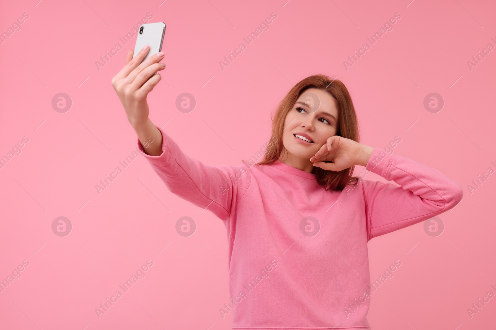 Photo of Beautiful woman taking selfie on pink background