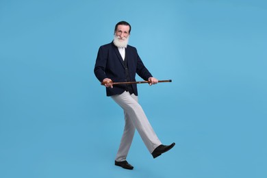 Senior man with walking cane on light blue background