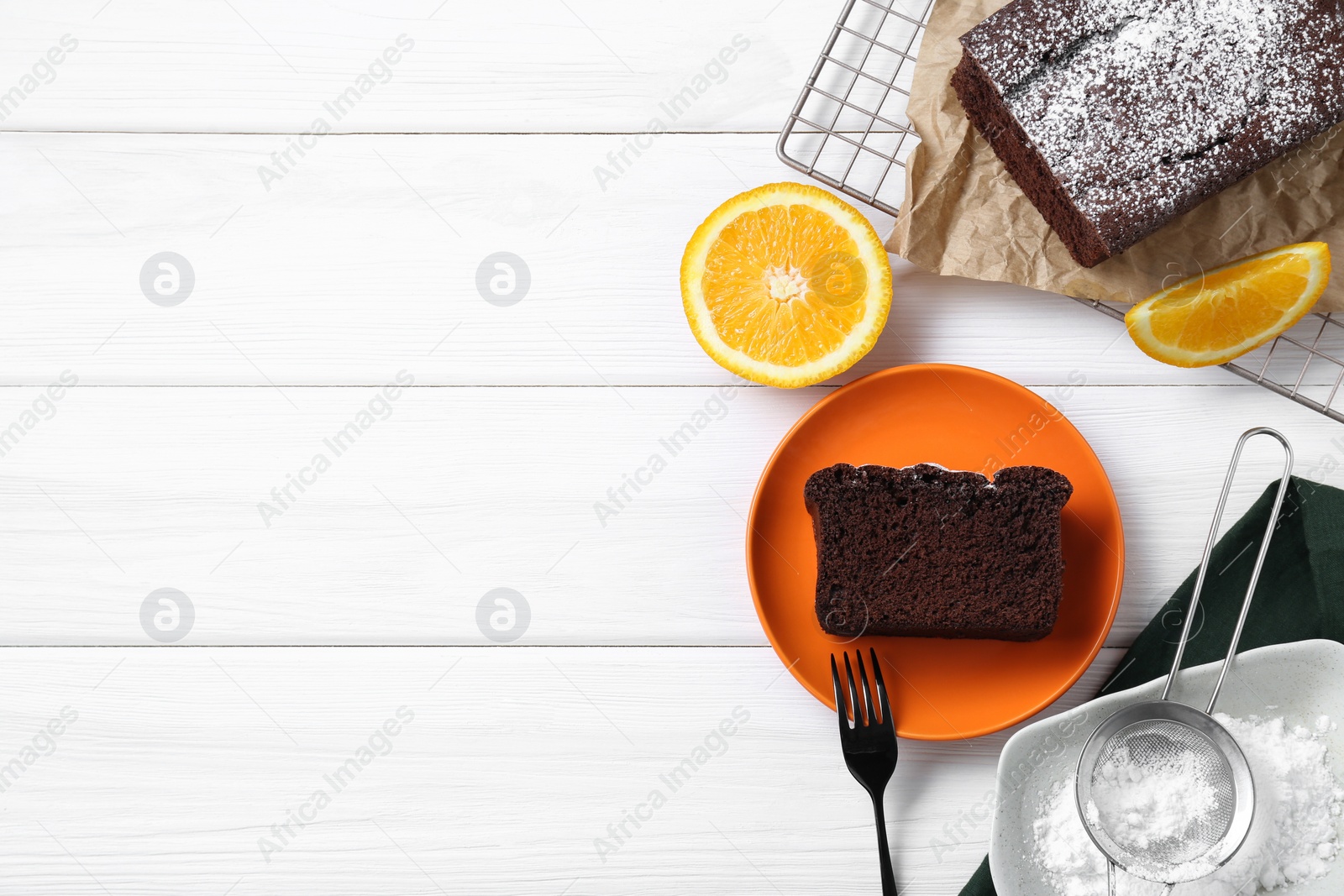 Photo of Tasty chocolate sponge cake and ingredients on white wooden table, flat lay. Space for text