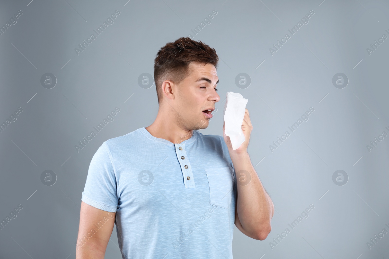 Photo of Young man suffering from allergy on grey background