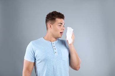 Young man suffering from allergy on grey background