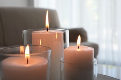 Burning candles in glass holders indoors, closeup