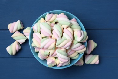 Photo of Bowl with colorful marshmallows on blue wooden table, flat lay