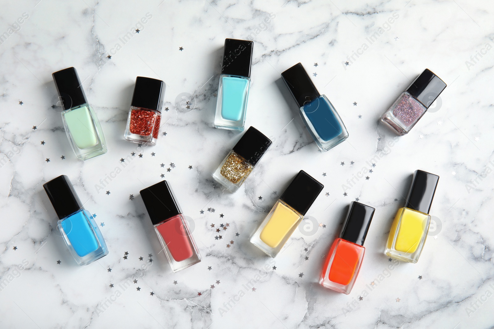 Photo of Bottles of nail polish on marble background, top view