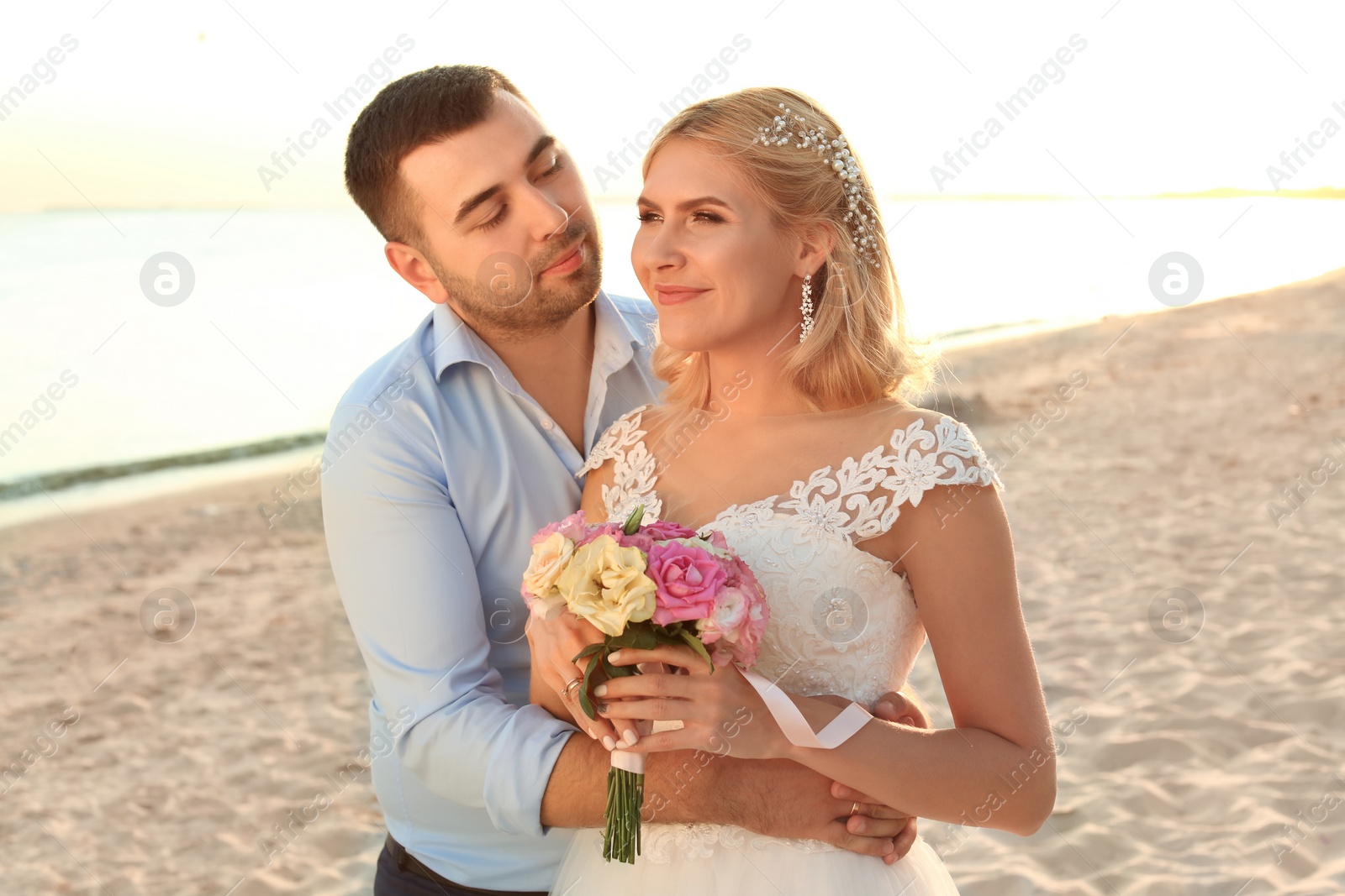 Photo of Wedding couple. Bride and groom hugging on beach at sunset