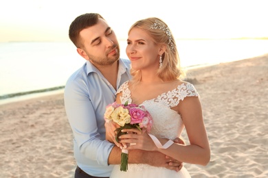 Wedding couple. Bride and groom hugging on beach at sunset