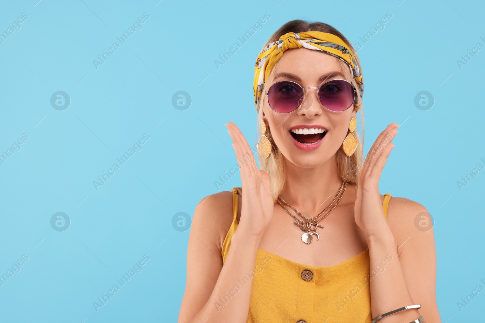 Photo of Portrait of emotional hippie woman in sunglasses on light blue background. Space for text