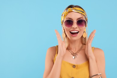 Photo of Portrait of emotional hippie woman in sunglasses on light blue background. Space for text