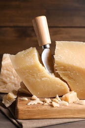 Parmesan cheese with wooden board and knife on table, closeup