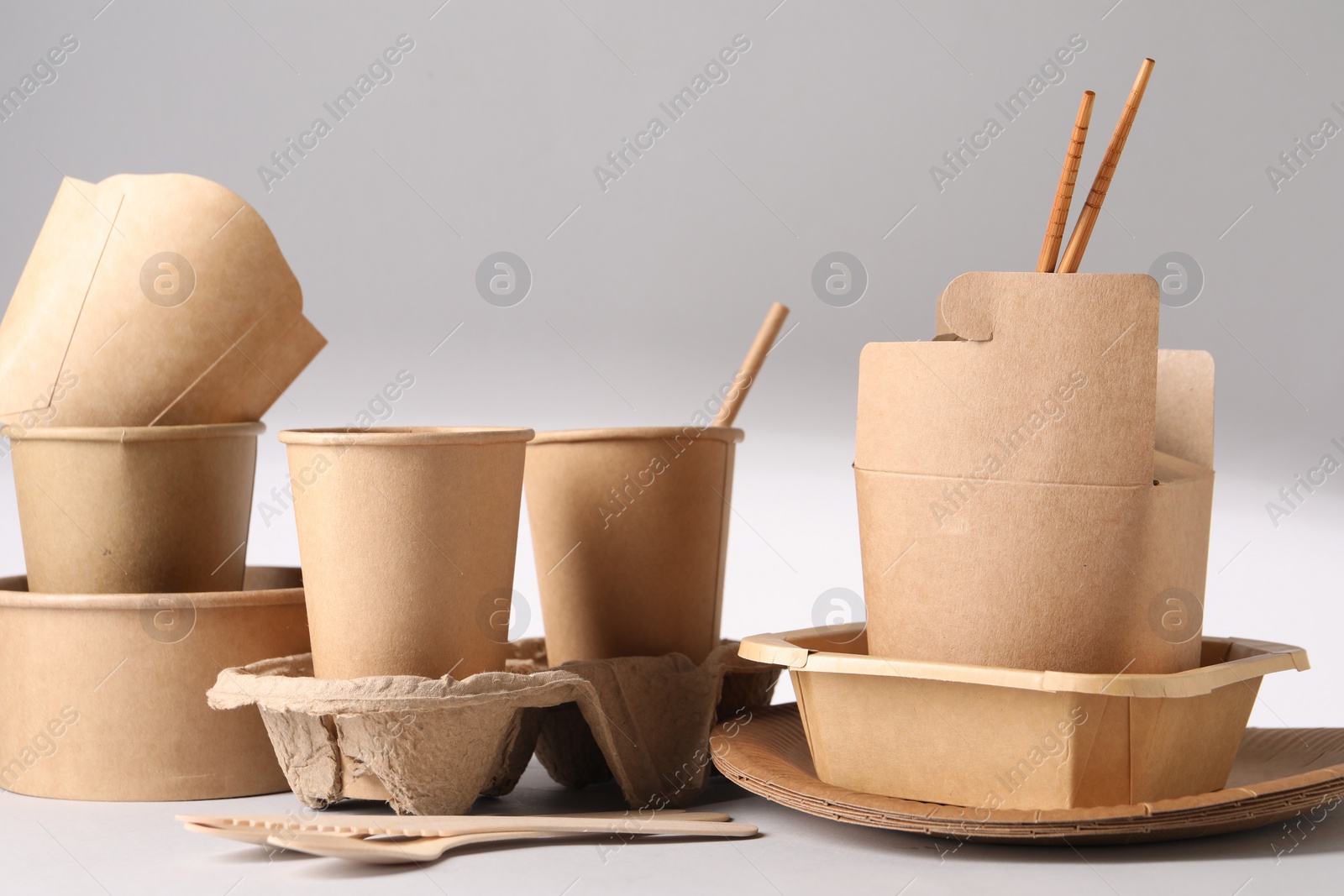 Photo of Eco friendly food packaging. Paper containers and tableware on light background