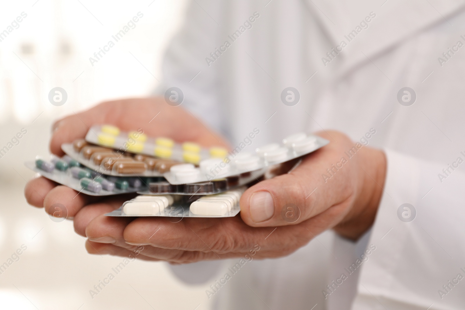 Photo of Senior pharmacist with pills on blurred background, closeup