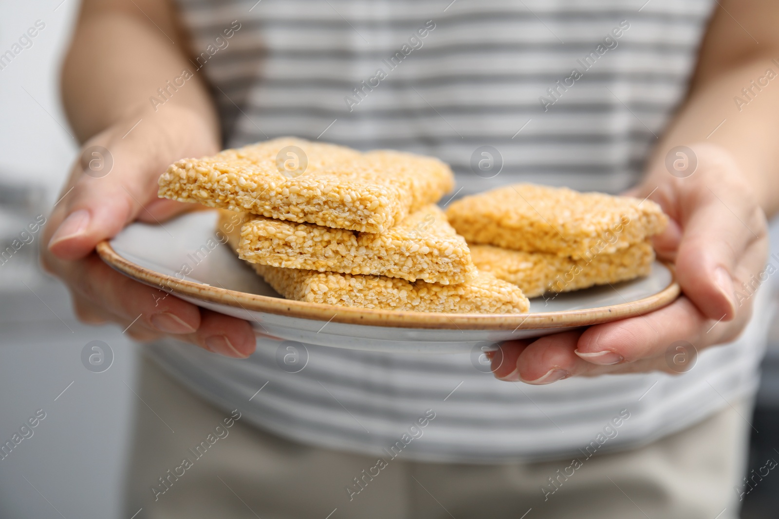 Photo of Woman holding delicious sesame kozinaki bars, closeup