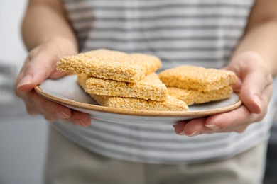 Woman holding delicious sesame kozinaki bars, closeup