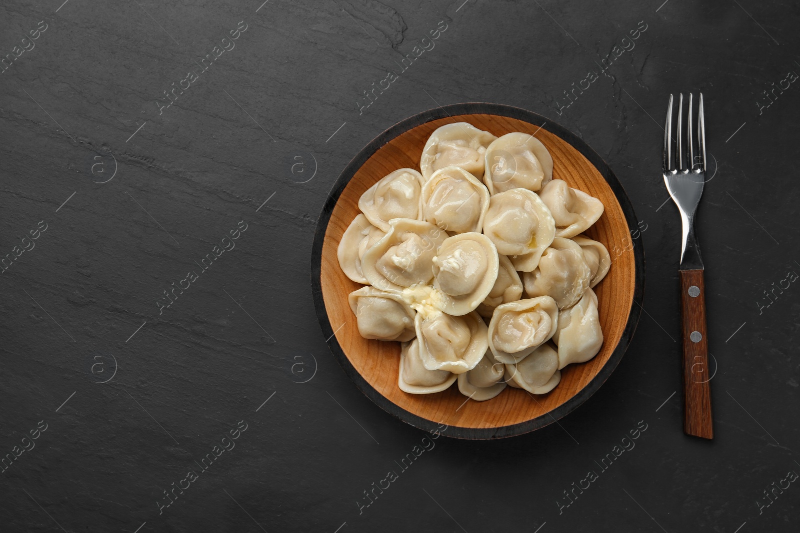 Photo of Tasty dumplings with butter on black table, flat lay. Space for text