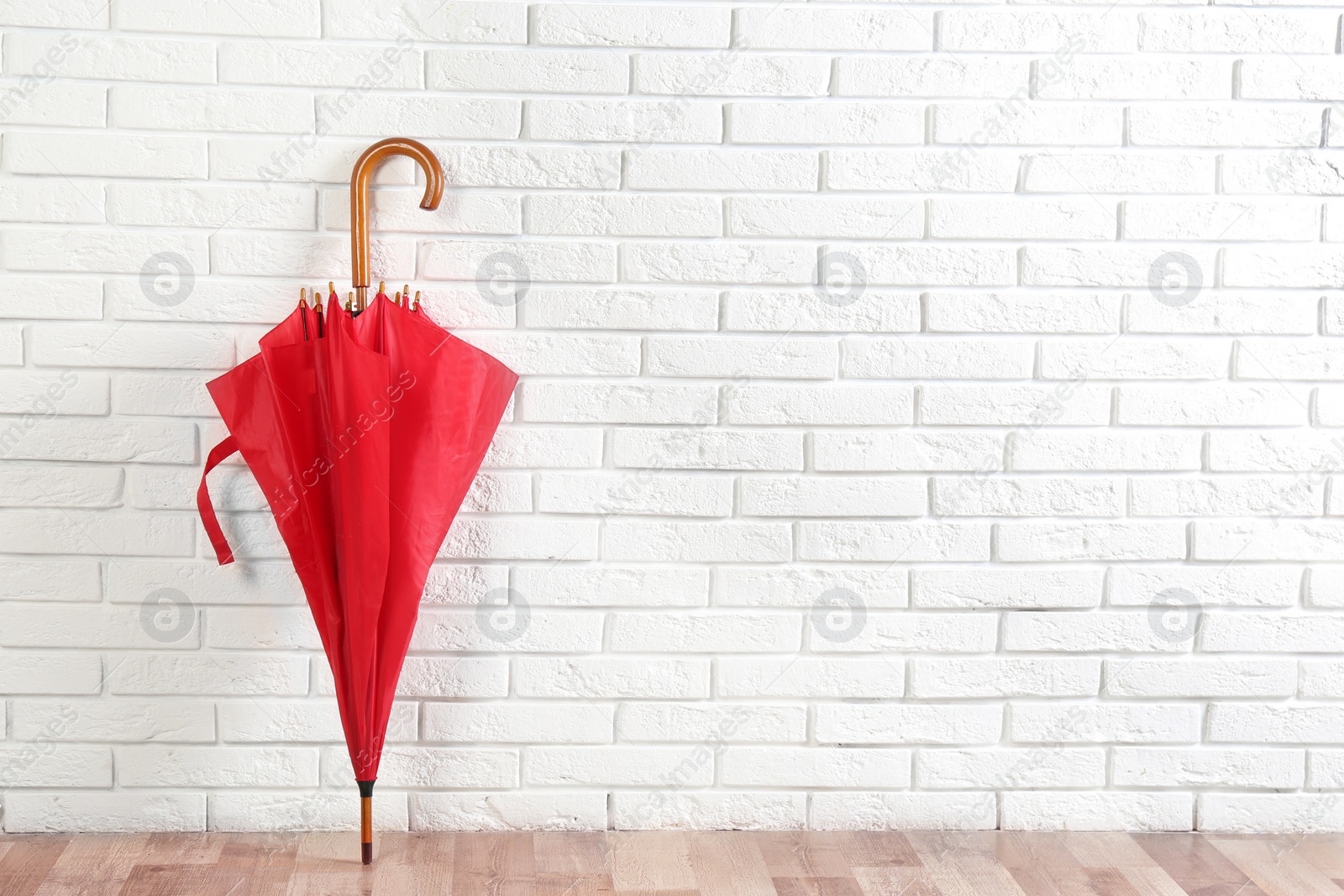 Photo of Beautiful red umbrella near white brick wall. Space for text