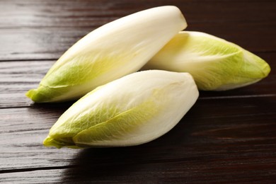 Photo of Raw ripe chicories on wooden table, closeup