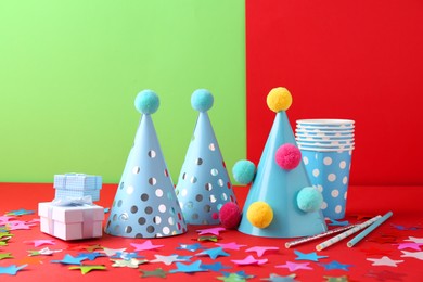 Photo of Party hats and other bright decor on color background