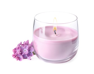 Pink wax candle in glass holder and lilac flowers isolated on white