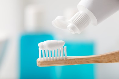 Photo of Applying toothpaste on brush against blurred background, closeup