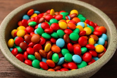 Photo of Bowl with tasty colorful candies on wooden table, closeup