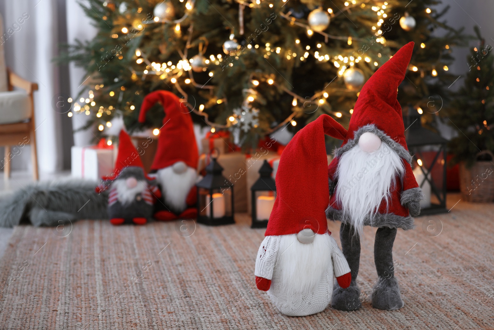 Photo of Cute Scandinavian gnomes on carpet near Christmas tree indoors