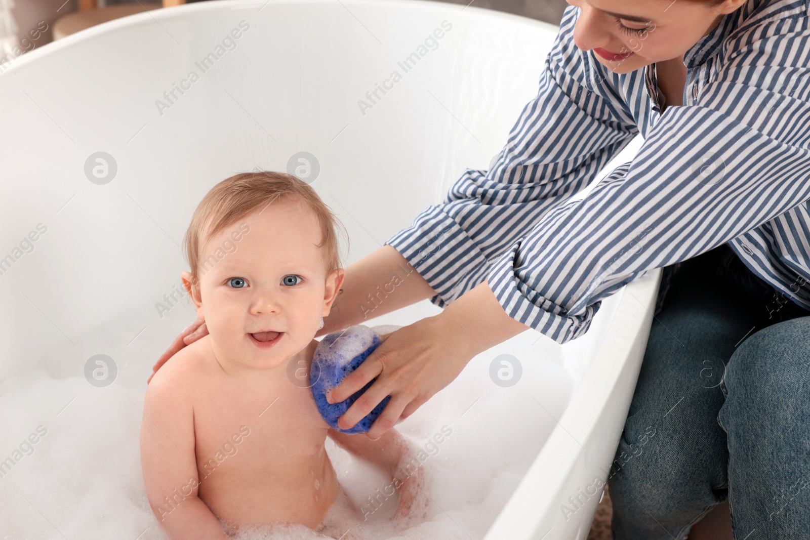 Photo of Mother washing her little baby in tub at home, closeup