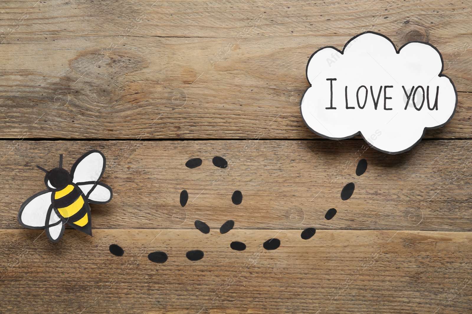 Photo of Card design with paper bee and phrase I Love You. Composition on wooden background, flat lay